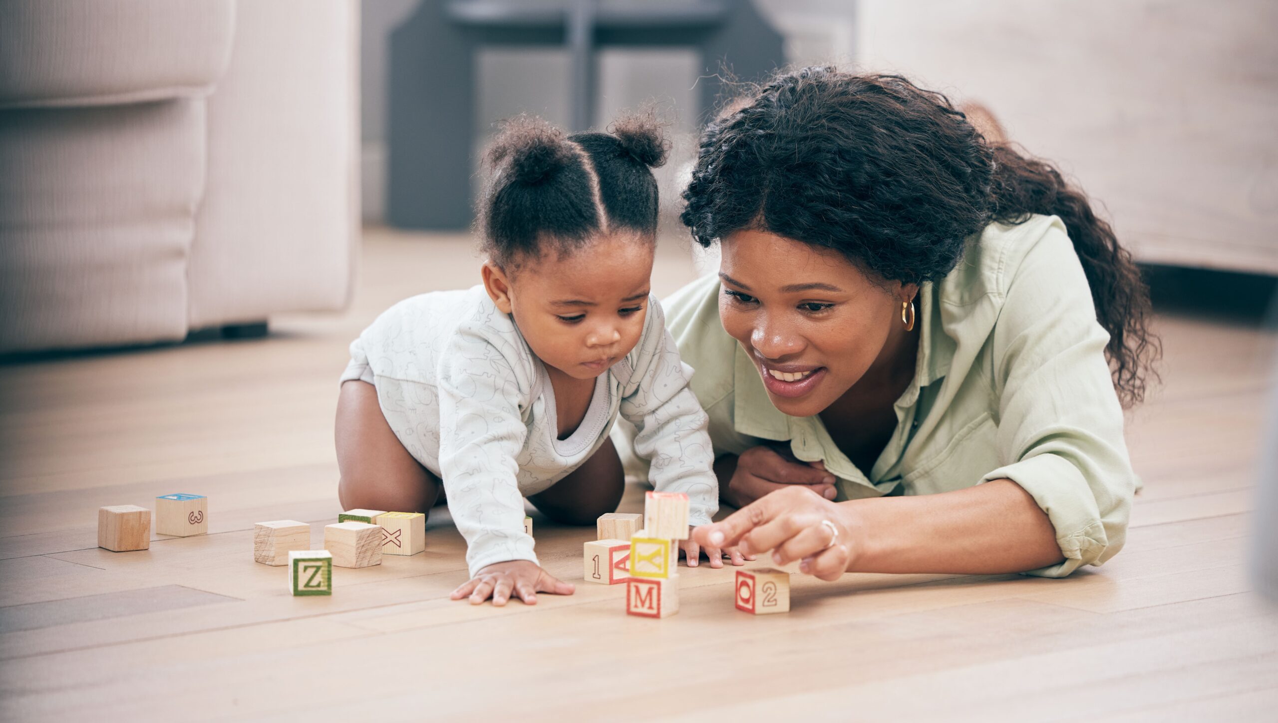 A mother is playing with her child using building blocks to improve childhood development.