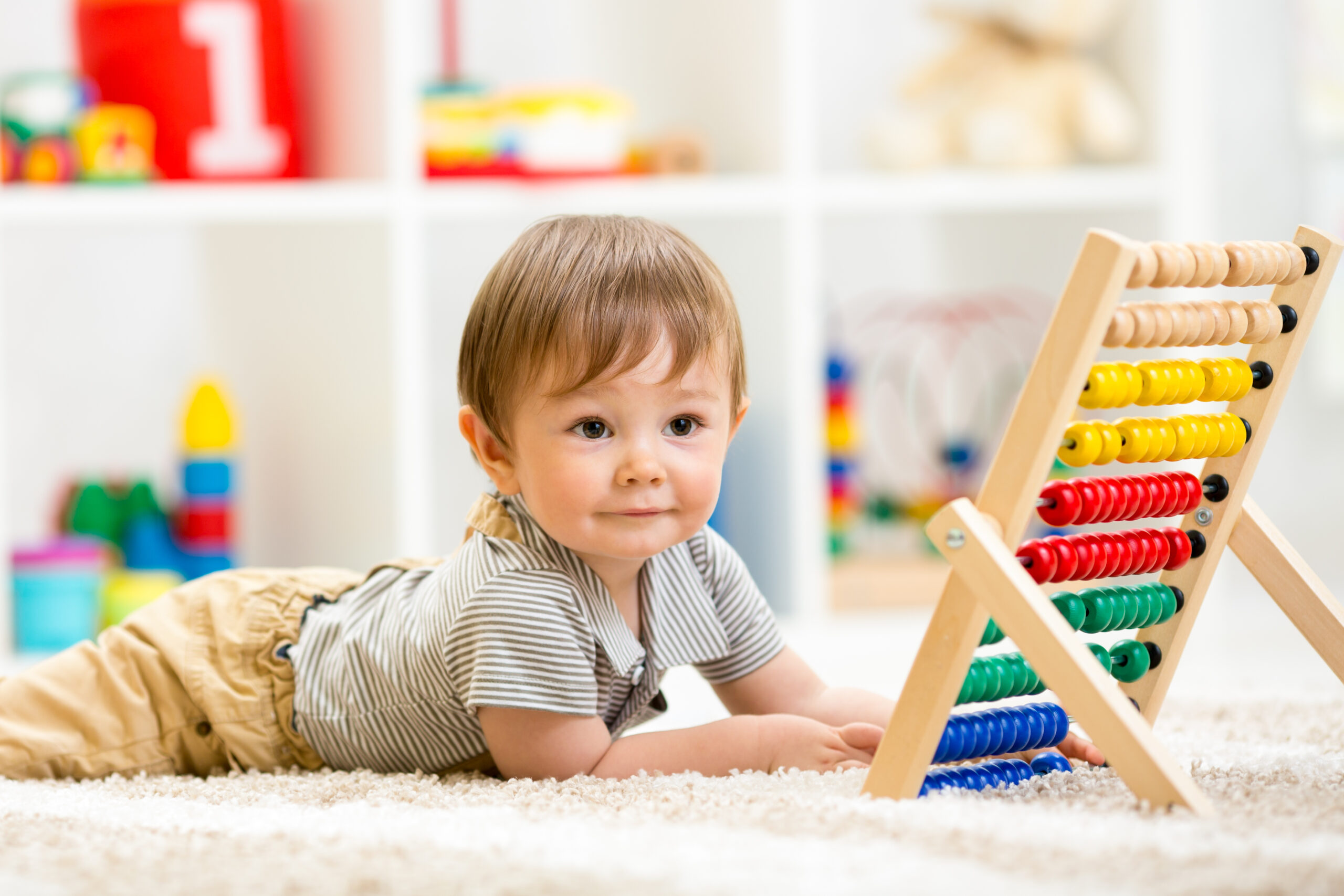 A baby is playing with an abacus in an early education center.