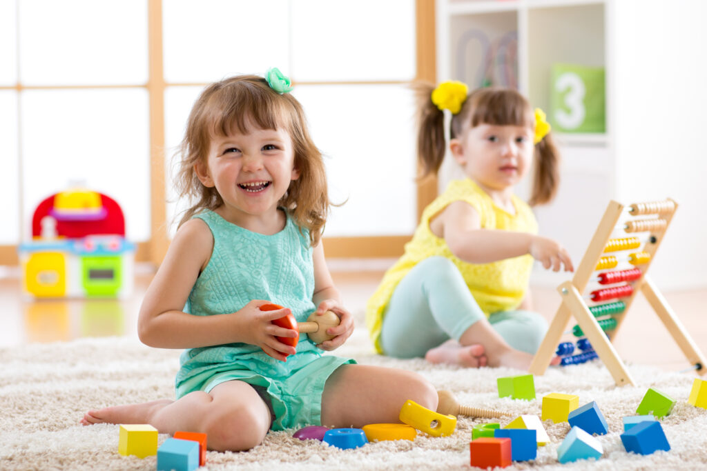 2 young children are playing with blocks at a childcare center.