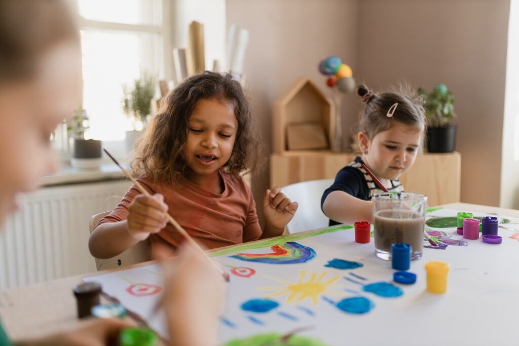 2 girls are painting in their childcare center