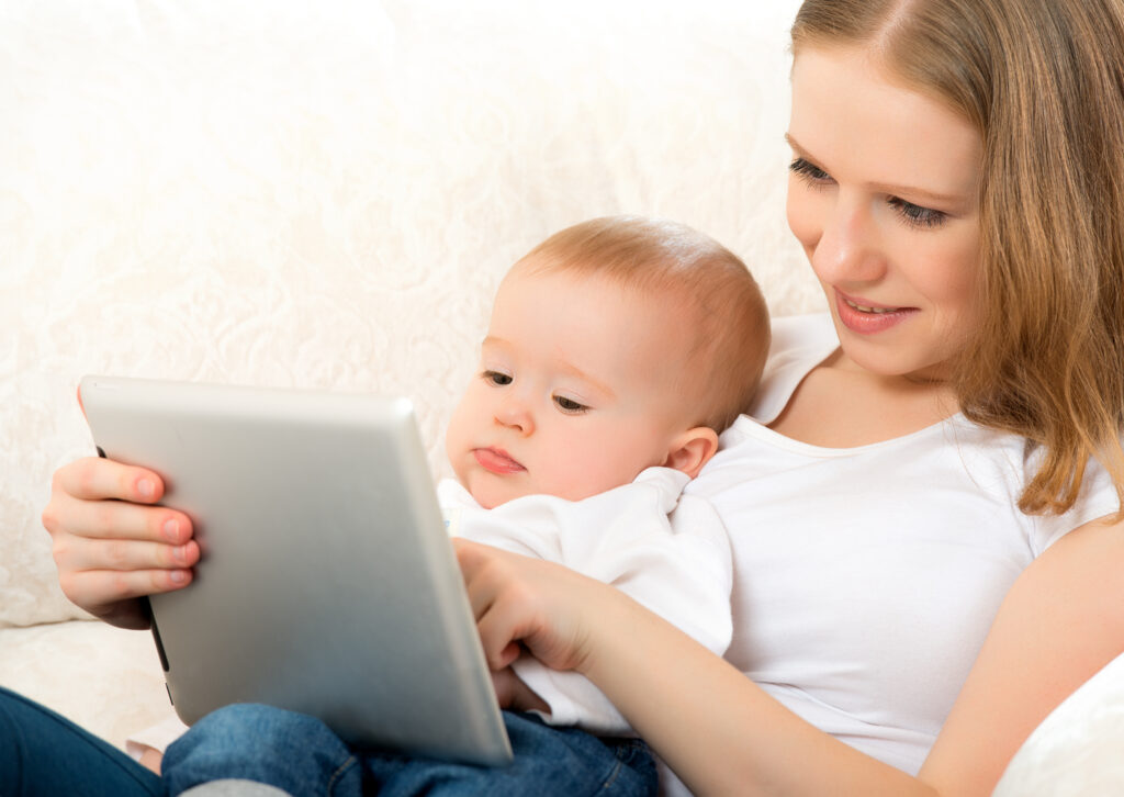 A baby and mother are using screen time with a tablet.