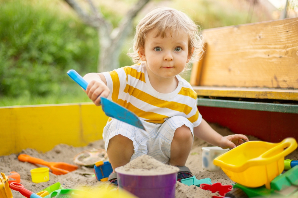 Toddler playing outside in a sandbox
